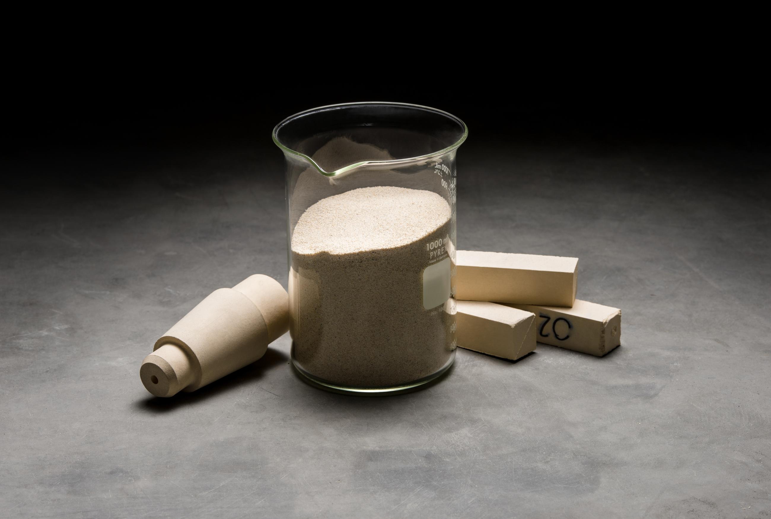 Zirconia material imagery with items in a glass beaker and on display around it, dramatically lit
